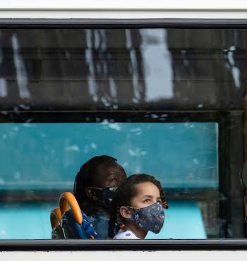 adult and young child wearing masks on the bus