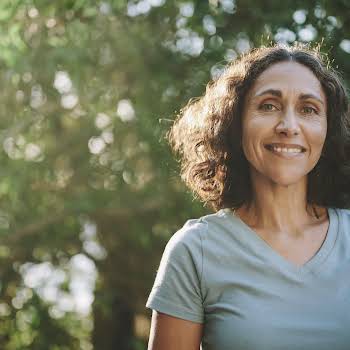 Smiling mature woman standing in a park outdoors in the summertime