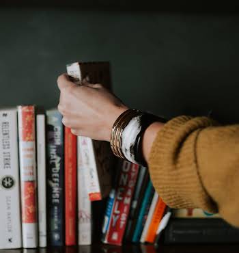 woman picking out book to read from shelf