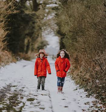 two children walking on a snow path in the country