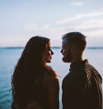 man and woman looking at each other in front of the water