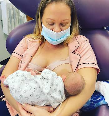 woman holding newborn baby and breastfeeding in a hospital chair
