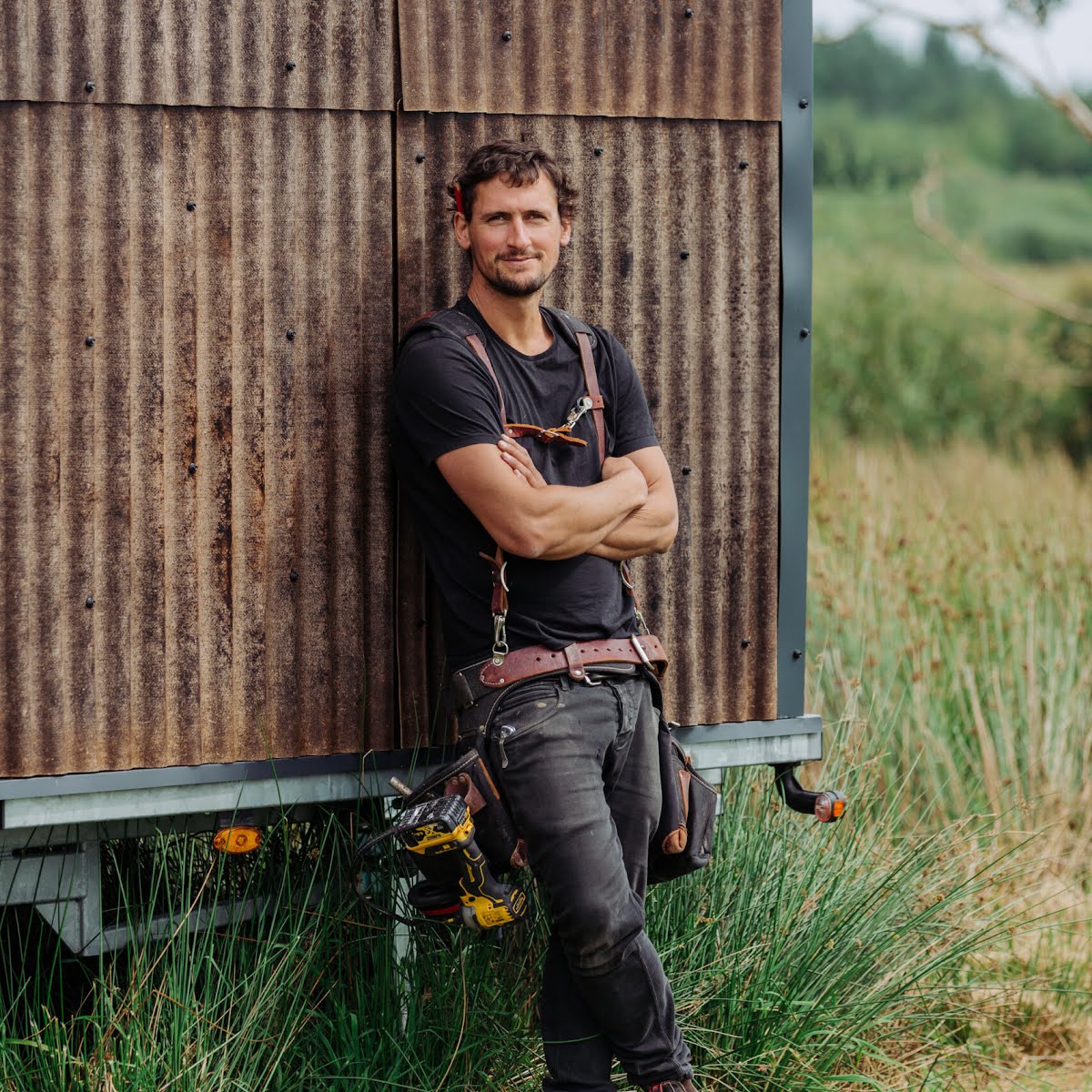 Harrison leaning on a Tigín clad in eco-friendly, hemp-fibre corrugated panels sourced from Margent Farm in the UK.