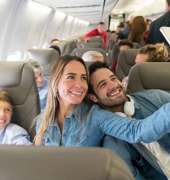 Happy family traveling by plane and taking a selfie with a cell phone while smiling - travel concepts