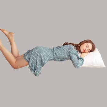 Relaxed girl in vintage ruffle dress levitating in mid-air, sleeping on stomach lying comfortable cozy on pillow