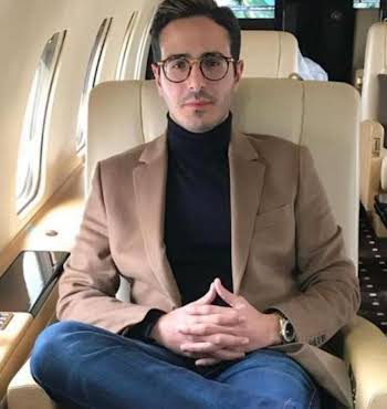 man wearing glasses sitting on a private jet