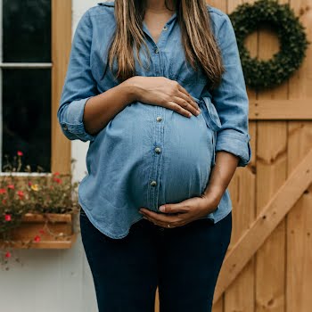 pregnant woman standing in front of Christmas wreath