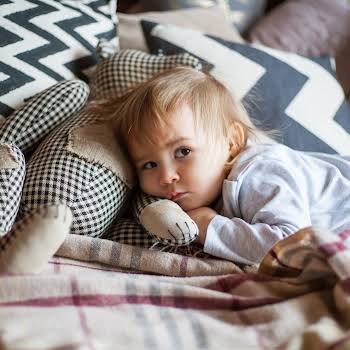Cute little girl in pajama hugging her toy hare on the bed at home, happy childhood concept, indoor portrait