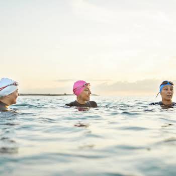 Women wearing swimming caps while talking in sea